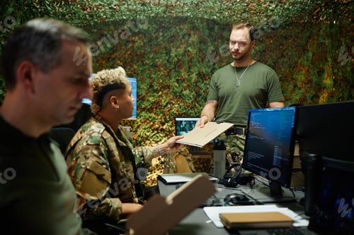 Preview: Young male officer in t-shirt passing folder with secret documents to colleague