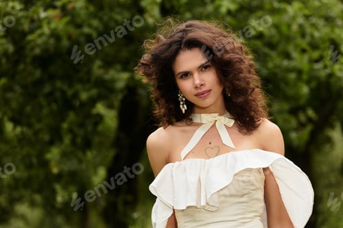 Preview: Curly-haired woman in white dress enjoying serene moments in lush green park