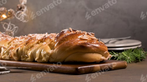 Preview: Braided Sweet Christmas Bread with Almonds and Icing Sugar on a Wooden Board