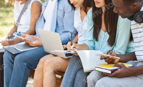 Preview: Diverse students studying outdoors in campus with books and devices