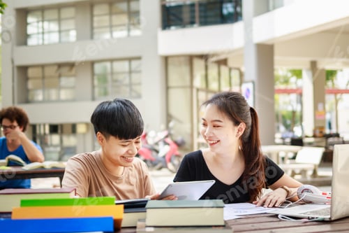 Preview: A happy group of attractive young people is tutoring exams with study books, sitting on study table