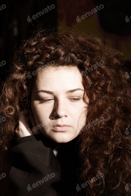Preview: Portrait Of A Beautiful Curly-Haired Girl With Redheads On A Gray Background