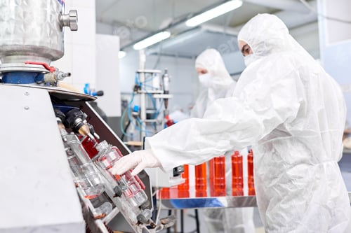 Preview: Factory worker putting plastic bottle into filling machine