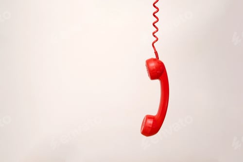 Preview: Red telephone receiver hanging by coiled cord on light grey background with copy space