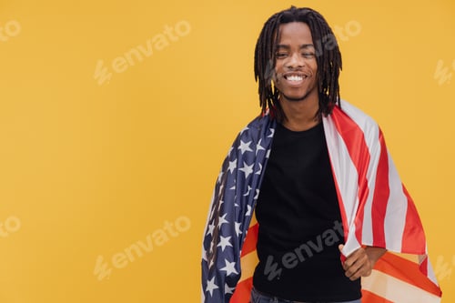 Preview: Young Man Smiling and Holding United States Flag on Yellow Background