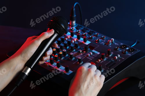 Preview: Woman holding microphone while working with professional mixing console at table, closeup