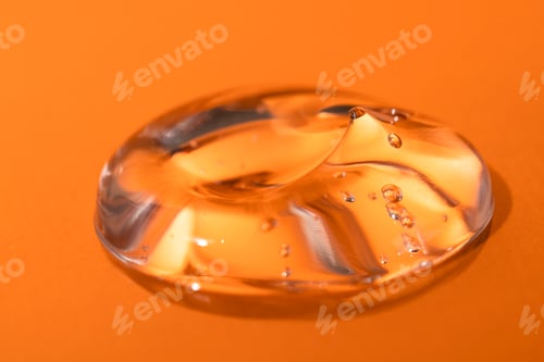 Preview: A drop of cosmetic transparent gel on a bright orange background.