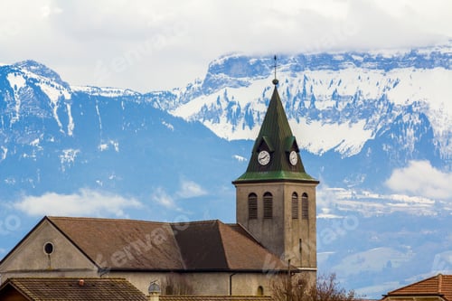 Preview: Dark contrast silhouette of church roof with tower against magnificent Alps mountains