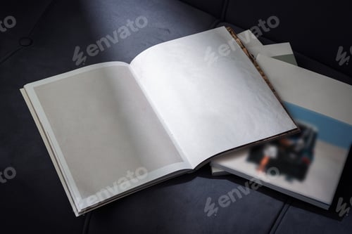 Preview: Stack of Magazines on a Black Leather Couch in Soft Light