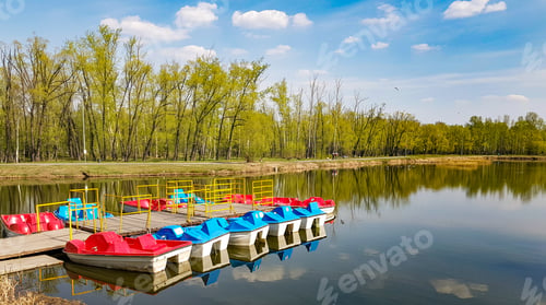 Preview: Colorful catamarans stand in a row at the wooden pier. Calm surface of the lake for water recreation