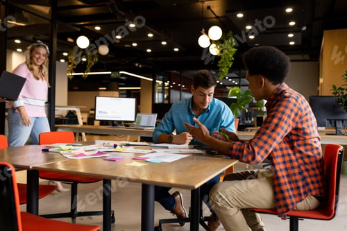 Preview: Diverse male colleagues in discussion at table in casual office meeting