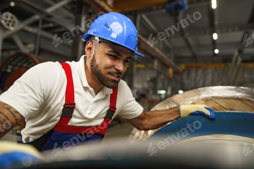 Preview: A young factory workman rolls heavy coil of electric cable