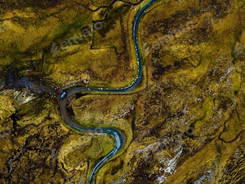 Vista previa: an aerial photo of a river winding through a landscape with grass, rocks and other