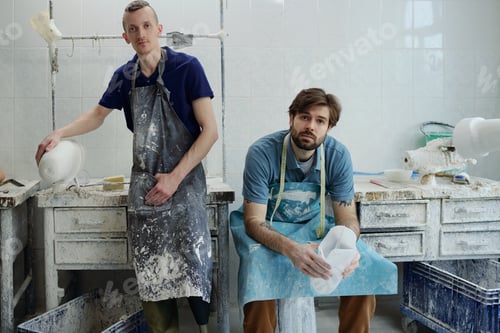 Preview: Staff of contemporary prosthetic factory in aprons looking at camera