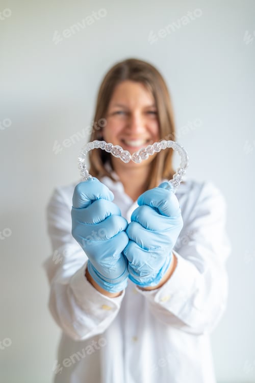 Preview: Dentist showing invisible braces aligner, heart shape, for orthodontic treatment