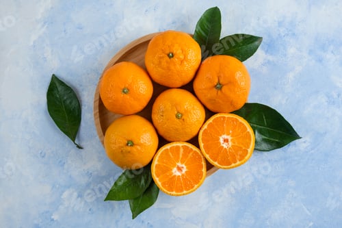 Preview: Top view of clementine mandarins with leaves on wooden plate