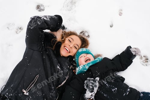 Vorschau: Mutter und Junge liegen im Schnee, lächeln und genießen den Moment