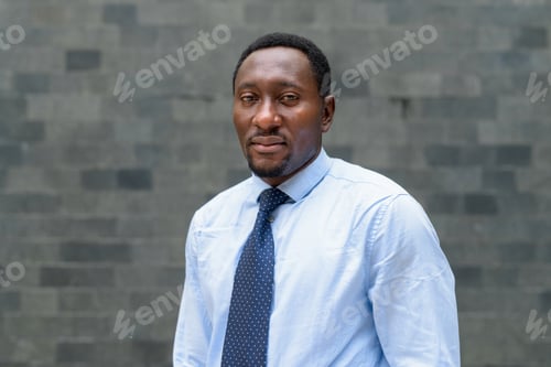 Preview: Portrait of handsome African businessman in city looking at camera