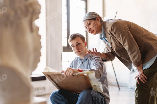 Preview: Mature teacher talking with her student during class in art school