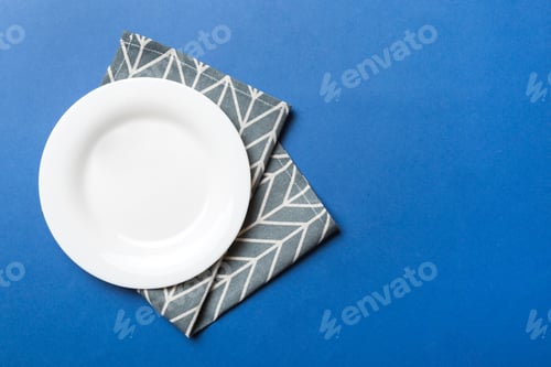Preview: Top view on colored background empty round white plate on tablecloth