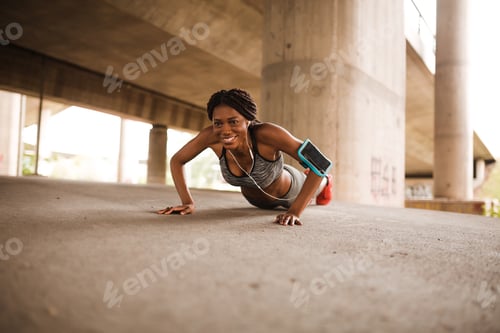 Preview: Motivated black woman doing push-ups outdoors