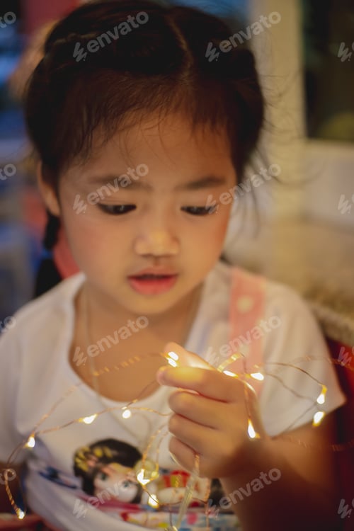 Preview: Young Child Playing with Glowing String Lights