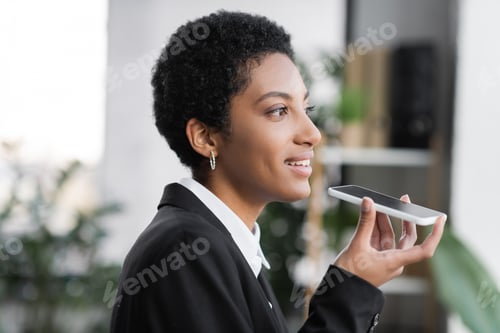 Preview: profile of positive african american businesswoman sending voice message on mobile phone while