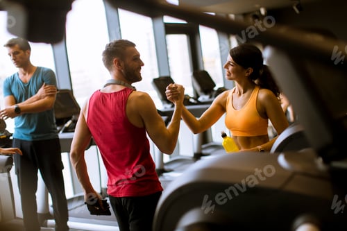 Preview: Young woman and personal trainer rest in the gym after workout