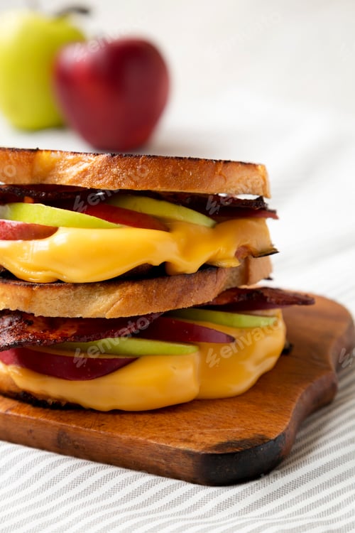 Preview: Homemade Bacon Apple Grilled Cheese on a rustic wooden board, side view. Close-up.