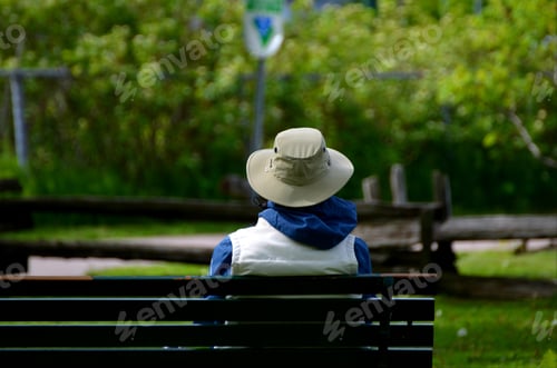 Preview: Person sitting alone on a park bench enjoying the fresh air and morning sun