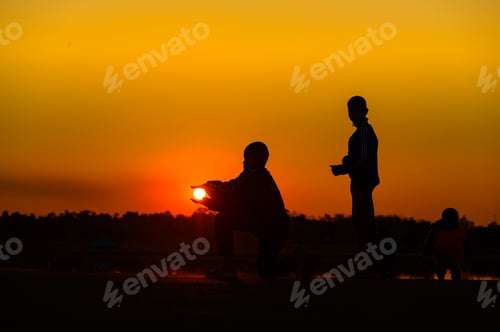 Preview: Child silhouette playing fun with many friends and playing against the sunset.