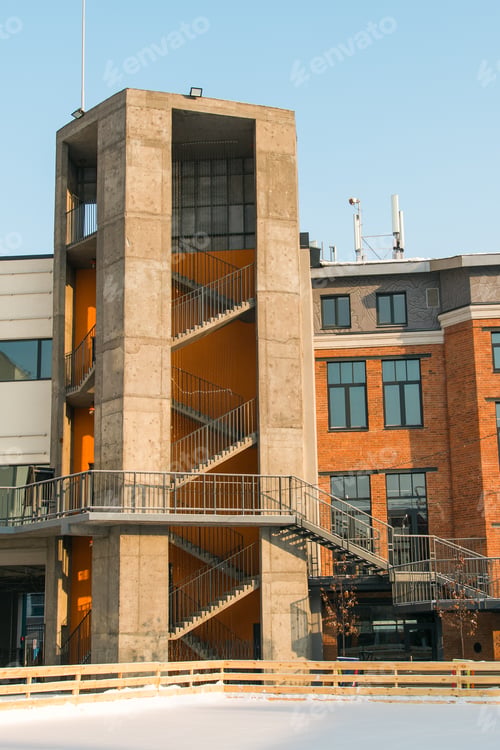 Preview: Facade of red brick building with outdoor iron stairs. Industrial building converted into offices