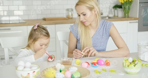 Preview: Mother looking at girl coloring eggs