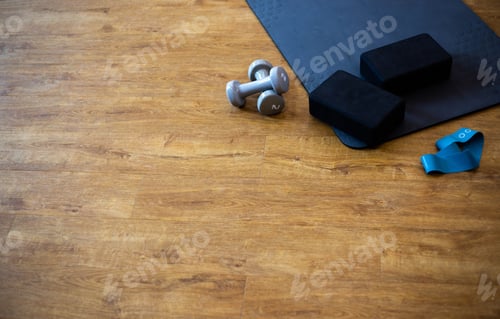 Preview: Fitness sports equipment set with yoga mat and dumbbells on gym floor. Background with copy space.
