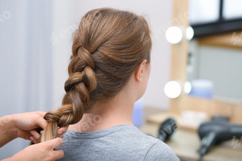 Preview: Professional coiffeuse braiding client's hair in salon