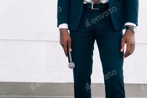Preview: cropped image of african american businessman holding microphone during seminar in conference hall