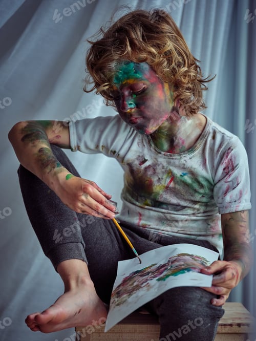Preview: Boy with arm put on knee holding paintbrush and drawing
