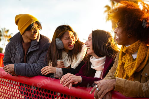 Preview: Happy multiracial friends laughing and talking enjoying sunny winter day. People having fun in city.