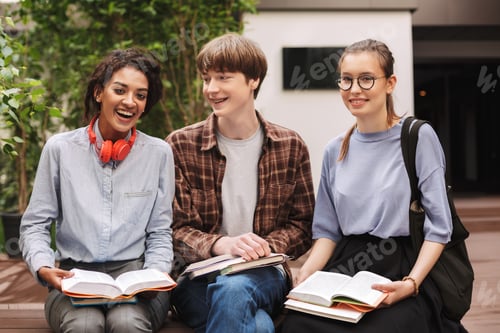 Preview: Group of students sitting on bench with books and happily looking in camera