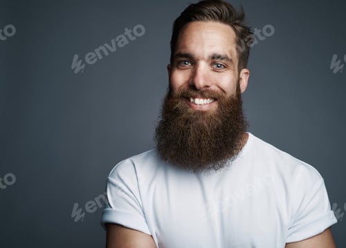 Preview: Bearded young man smiling against a gray background