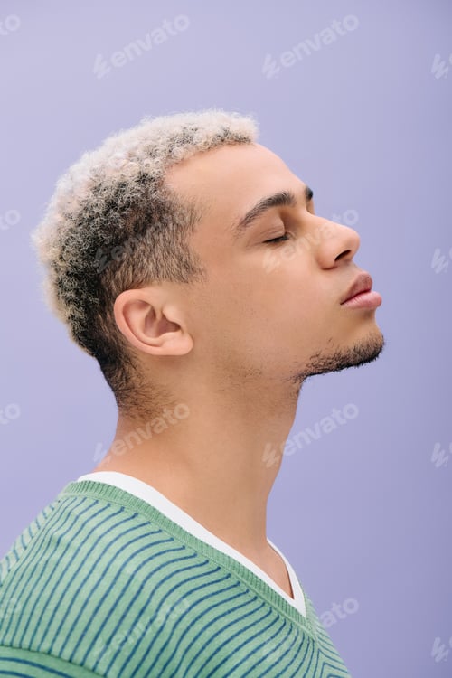 Preview: Young man showcases stylish confidence against a vibrant purple backdrop