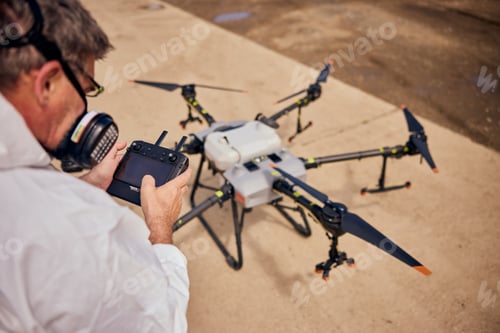 Preview: Top view of a male using a controller and setting up the agro drone.