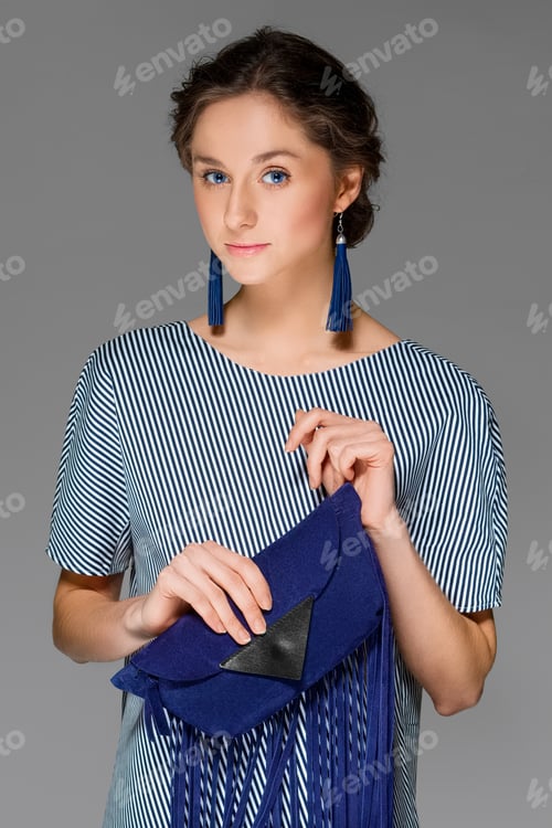 Preview: attractive lady in dress in stripes posing in studio with bag