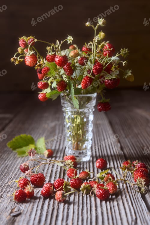 Preview: Wild strawberries in glass vase on rustic wooden table