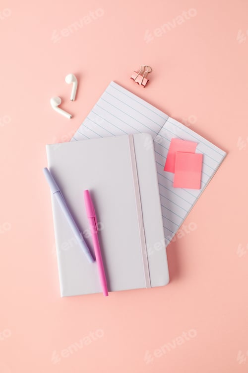 Preview: Notepad, pens and wireless headphones on a pink background. Online learning, desktop.