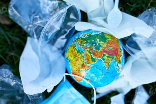 Preview: A globe in a pile of scattered garbage on a background of green grass