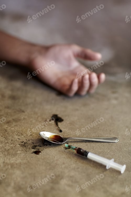 Preview: His last high. Close up shot of a drug addicts limp arm with drug paraphernalia lying next to it.