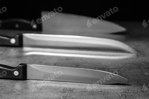 Preview: Sharp knives on table against dark background