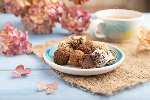 Preview: Chocolate truffle candies with cup of coffee on a blue wooden background and linen textile