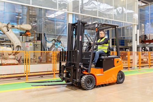 Preview: Storehouse employee in uniform working on forklift in modern automatic warehouse. Boxes are on the